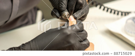 Manicure master uses electric nail file machine in a nail salon, close up Manicure master uses electric nail file machine in a nail salon, close up 88715029