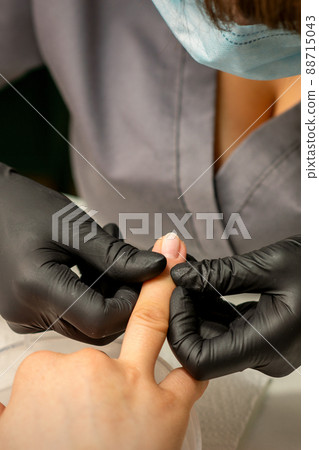 Close up professional manicure master holds the female hand of the customer and checks the manicure in a nail salon 88715043