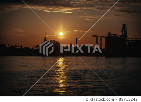 Gorgeous scenic of Thai temple silhouettes and Industrial factory along Chao phraya river over sun at sunrise. Gorgeous scenic of Thai temple silhouettes and Industrial factory along Chao phraya river over sun at sunrise. 88715242