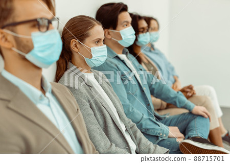 Colleagues wearing face masks and sitting on chairs Colleagues wearing face masks and sitting on chairs 88715701