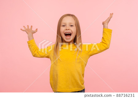Happy carefree child emotions. Energetic joyful adorable little girl raising hands and screaming with happiness, rejoicing victory, laughing at joke. indoor studio shot isolated on pink background Happy carefree child emotions. Energetic joyful adorable little girl raising hands and screaming with happiness, rejoicing victory, laughing at joke. indoor studio shot isolated on pink background 88716231