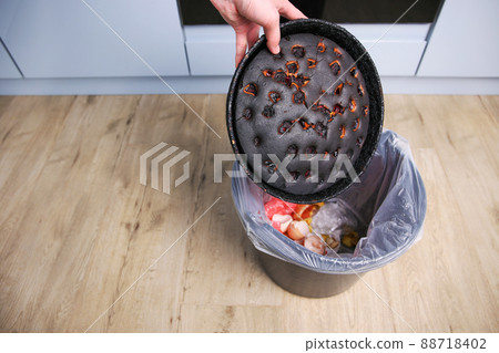 A woman throws a burnt pie in the trash. 88718402