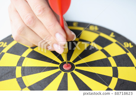 Female hand put red dart arrow right in center of dartboard, hit goal or put new aim Female hand put red dart arrow right in center of dartboard, hit goal or put new aim 88718623