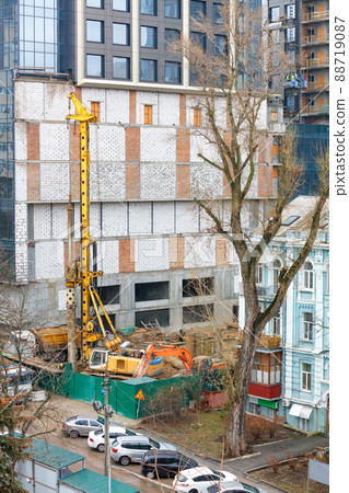 A heavy excavator along with a drilling rig mechanism works at a construction site. A heavy excavator along with a drilling rig mechanism works at a construction site. 88719087