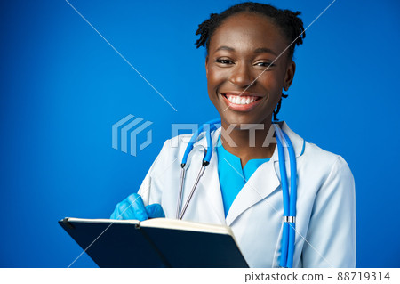 Black female doctor student wearing a lab coat with book Black female doctor student wearing a lab coat with book 88719314