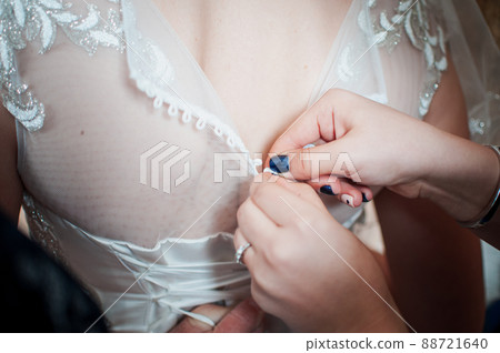 Bridesmaids assist bride to wear wedding dress 88721640