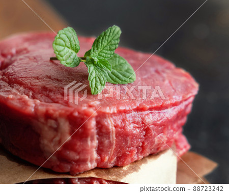Raw beef fillet steaks with mint on wooden board on dark background close up 88723242