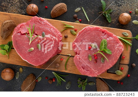 Raw beef fillet steaks with herbs and spices on wooden board on dark table top view 88723243