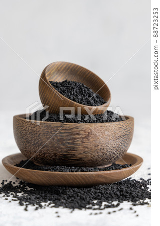 Indian spice Black cumin (nigella sativa or kalonji) seeds in wooden bowls on white table close up 88723253