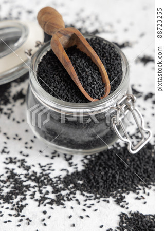 Indian spice Black cumin (nigella sativa or kalonji) seeds in glass jar with a wooden scoop close up 88723255