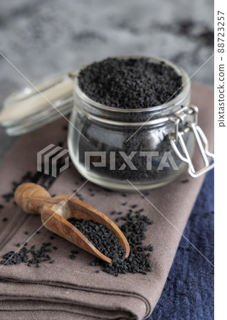 Indian spice Black cumin (nigella sativa or kalonji) seeds in glass jar with a wooden scoop close up Indian spice Black cumin (nigella sativa or kalonji) seeds in glass jar with a wooden scoop close up 88723257