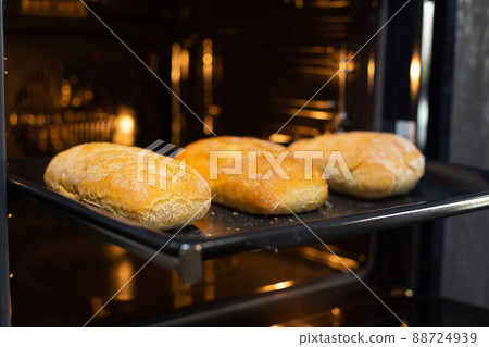 Close-up. The cook prepares bread in an electric oven. 88724939