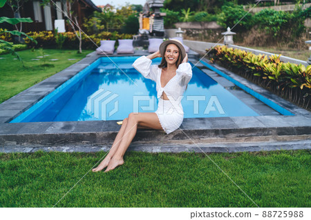 Positive woman sitting on poolside Positive woman sitting on poolside 88725988