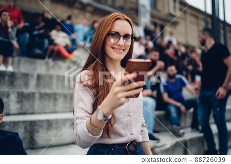 Happy Caucasian woman with red hair using smartphone technology Happy Caucasian woman with red hair using smartphone technology 88726039