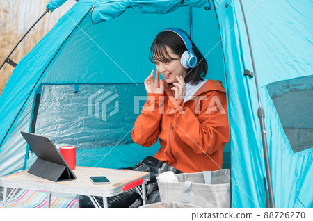A woman enjoying a streaming service at a solo camp 88726270