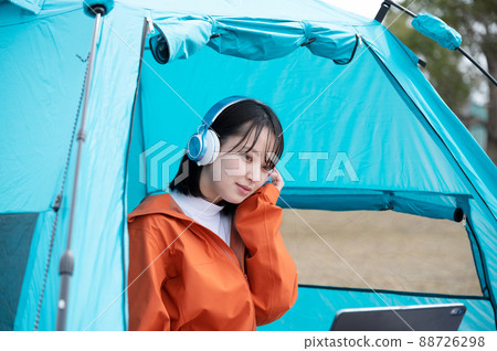 A woman enjoying a streaming service at a solo camp 88726298