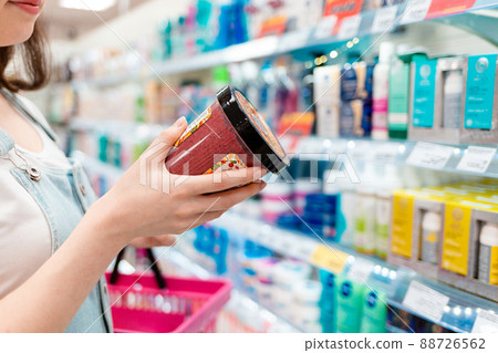 Shopping. The woman is holding a body cream. A jar of cream and hands close-up 88726562