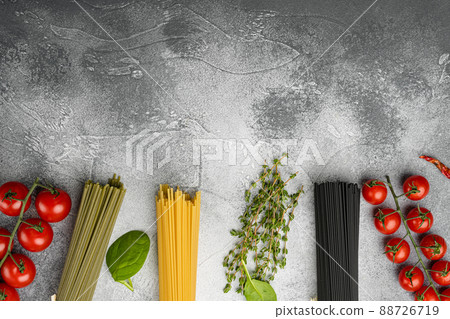 Multi colored spaghetti with ingredients, on gray stone table background, top view flat lay, with copy space for text Multi colored spaghetti with ingredients, on gray stone table background, top view flat lay, with copy space for text 88726719
