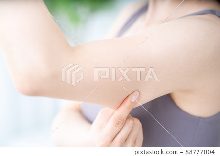 A woman checking the slack in her upper arm [Parts cut] 88727004