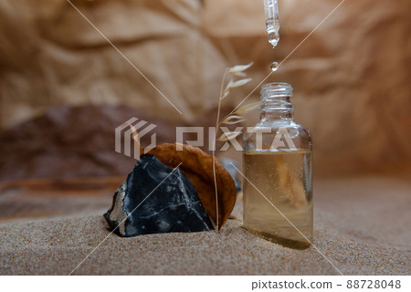 Bottle with a pipette, filled with essence, oil or perfume. Background sand and craft paper. 88728048