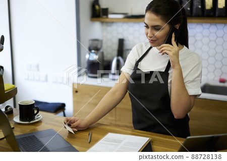 20s smiling professional woman barista checking online booking via technology 20s smiling professional woman barista checking online booking via technology 88728138