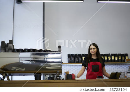 Confident female entrepreneur owner of cafe in apron enjoying job as barista in bakery Confident female entrepreneur owner of cafe in apron enjoying job as barista in bakery 88728194