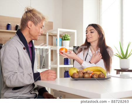 young female nutritionist in office suggests eating fruits to her patient young female nutritionist in office suggests eating fruits to her patient 88728263