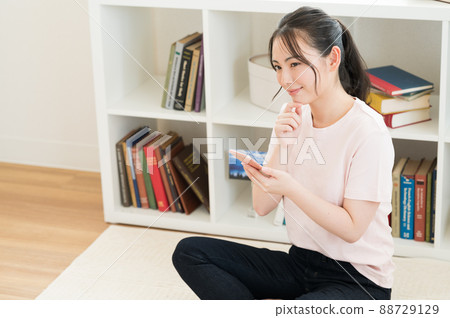 A woman who manipulates a smartphone in the living room 88729129