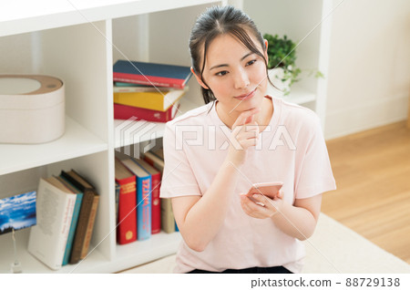 A woman who manipulates a smartphone in the living room 88729138