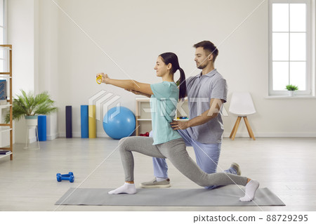 Side view of young woman doing forward lunges at physiotherapy rehabilitation clinic 88729295