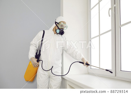 Pest control exterminator in suit and mask spraying insecticide over house window Pest control exterminator in suit and mask spraying insecticide over house window 88729314