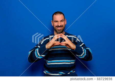 Cunning bearded man clasping hands and planning evil tricky prank or scheming, cheating with sly smile. Indoor studio shot isolated on blue background 88729656