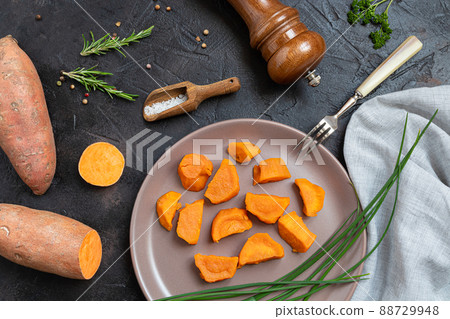 Baked sweet potatoes, raw yam and spices on a dark table - plant-based eating, top view 88729948