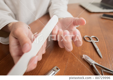 Close-up of hand of caucasian young woman doing manicure at home with nail supplies. 88729996