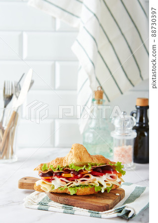 Croissant sandwich with cheese, ham, lettuce, tomatoes, olives and delicious sauce on wooden board. Croissant sandwich with cheese, ham, lettuce, tomatoes, olives and delicious sauce on wooden board. 88730397