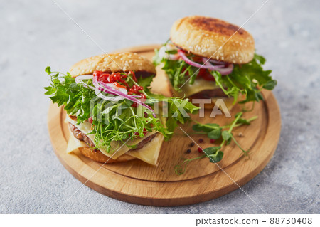 Two burgers with veal cutlet and herbs on wooden cutting board 88730408