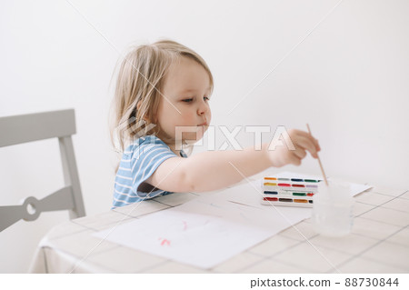 Child painting and drawing with watercolor paint at white table. Development of creative potential in children.  88730844