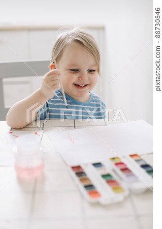 Child painting and drawing with watercolor paint at white table. Development of creative potential in children.  88730846