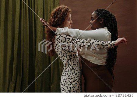 Two young girlfriends uniting and support each other against the brown background 88731425
