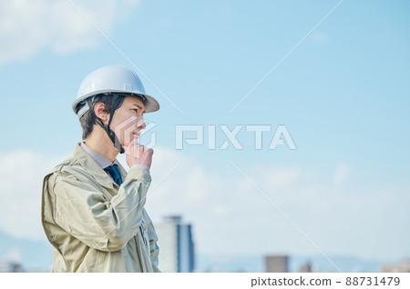 A young man in work clothes thinking against the blue sky 88731479