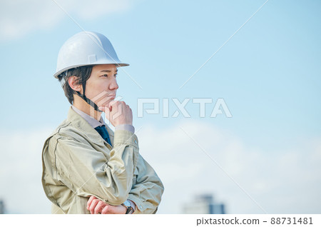 A young man in work clothes thinking against the blue sky 88731481