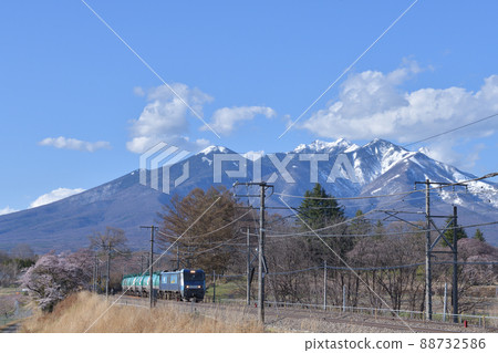 EH200 series freight train that goes to the Chuo Main Line in spring with Yatsugatake in the snow covered in Nagasaka Town, Hokuto City 88732586
