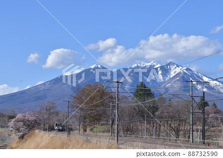 Trains and ordinary trains that go to the Chuo Main Line in spring with Yatsugatake in the snow covered in Nagasaka Town, Hokuto City 88732590