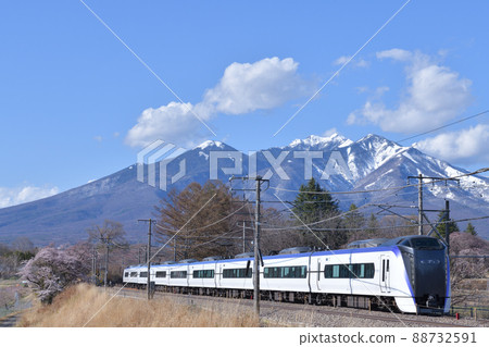 E353 Series Limited Express Azusa, a train that goes on the Chuo Main Line in the spring with Yatsugatake in the snow covered in Nagasaka Town, Hokuto City 88732591
