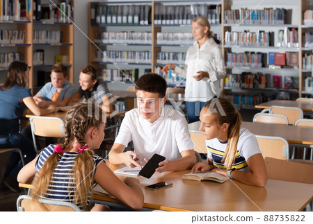 Cheerful boys and girls brainstorming in teams Cheerful boys and girls brainstorming in teams 88735822