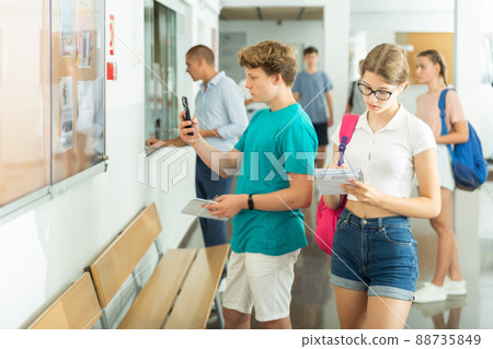 Teenagers standing and looking at schedule Teenagers standing and looking at schedule 88735849