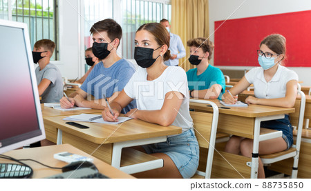 Teenagers in protective masks making notes of teacher lecture in college 88735850