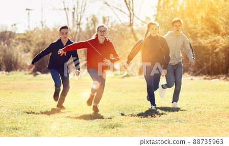Cheerful teens running on green lawn 88735963