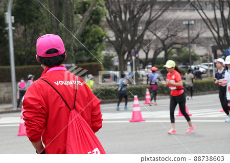 Volunteers watching over female runners running hard at marathon events 88738603
