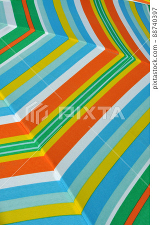 Closeup of green, orange, blue and white striped summer parasol 88740397